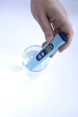 Suyun TDS ölçümü. Elektronik pH ölçer ve bir bardak su. Erkek eli.