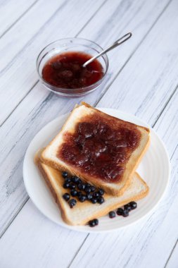 Hafif ahşap arka planda böğürtlenli tost ve reçel