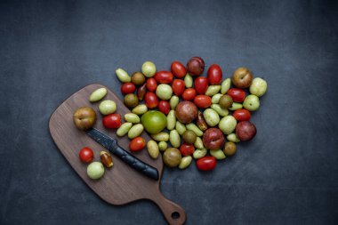 Çeşitli taze meyve, hurma, kiraz domatesleri, Longan, erik, koyu gri arka plan üzerine kuruludur..