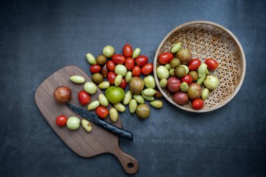 Çeşitli taze meyve, hurma, kiraz domatesleri, Longan, erik, koyu gri arka plan üzerine kuruludur..