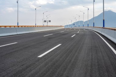 Şehir silueti olan boş asfalt karayolu.