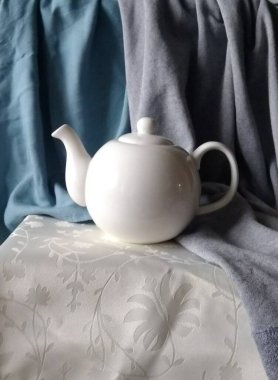 Beyaz porselen çaydanlık, kumaş arkaplanda çaydanlık.