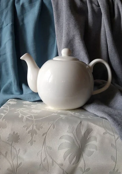 Beyaz porselen çaydanlık, kumaş arkaplanda çaydanlık.