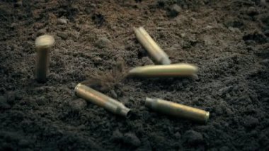 Tüfek ateşlenirken mermi kovanları yere düşüyor.