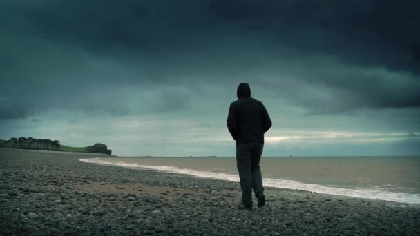 Man går på stenig strand — Stockvideo