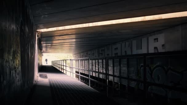 Mann läuft unter Brücke in dramatischer Beleuchtung — Stockvideo