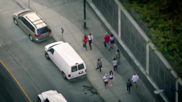 Κοιτάζοντας προς τα κάτω στο πεζοδρόμιο της πόλης, με τους ανθρώπους και τα αυτοκίνητα — Αρχείο Βίντεο