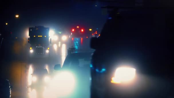 Vista cinematográfica de los coches que pasan en la noche lluviosa — Vídeo de stock