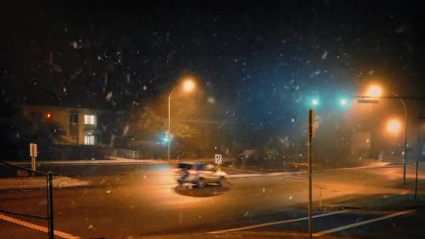 Coches en la ciudad por la noche con nieve cayendo — Vídeo de stock