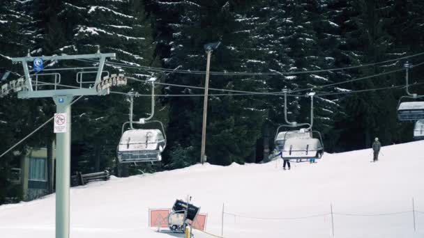 Люди катаются на лыжах по склону рядом с подъемником — стоковое видео