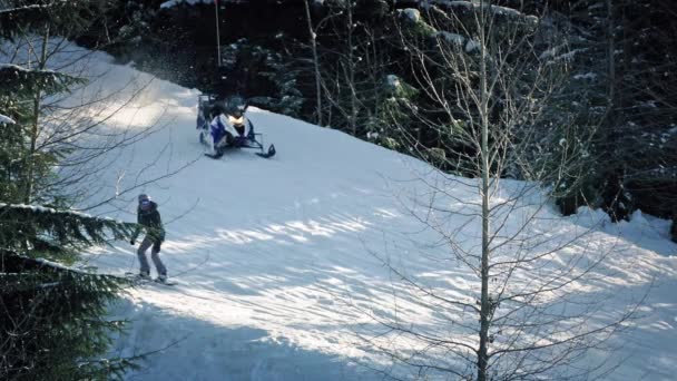 Esquiadores, motos de nieve y snowboarders pasan por la pista — Vídeo de stock