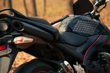 Sonbahar ormanlarında siyah stil spor motosikleti.