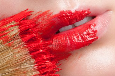 Red lips on a background of lush roses. Lips and flower close-up.
