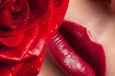 Red lips on a background of lush roses. Lips and flower close-up.