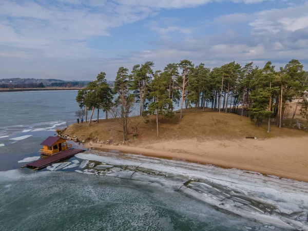 Vista aérea de gelo rachado no lago Kaunas e litoral com uma cabana de cima — Fotografia de Stock