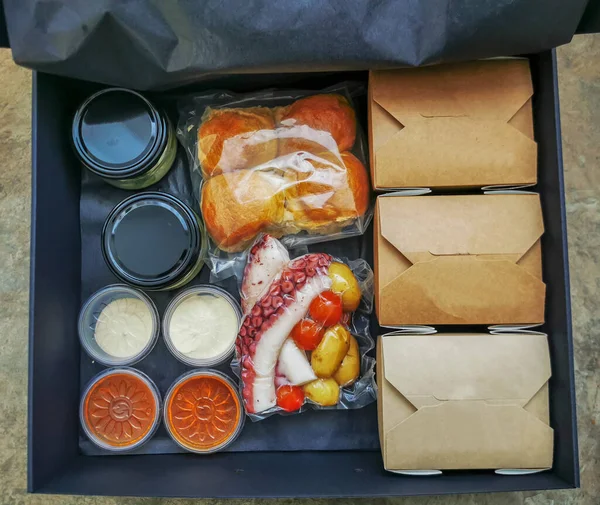 Caixa de presente com iguarias de comida preparada para comer. Polvo com guarnição e molhos — Fotografia de Stock