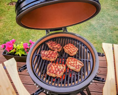 Kamado yumurtalı barbekü ızgarası canlı bir terasta bifteklerle duruyor.. 