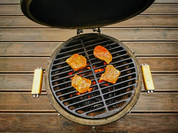 Een kamado type barbecue grill met biefstuk roosterend op een open vuur — Stockfoto