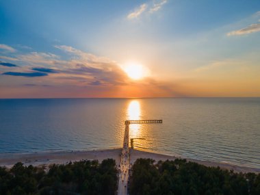 Palanga Köprüsü 'nün havadan görünüşü Baltık Denizi' ne doğru düz bir yol ve günbatımı
