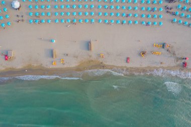 Rimini sahil şeridinin havadan çekilmiş fotoğrafı. Plajda birçok plaj şemsiyesi var.