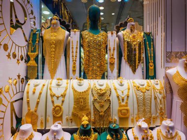 Store windows full of luxurious gold jewelry items on a storefront at the Dubai Gold Souk old gold market