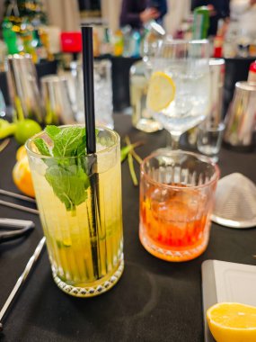 Karışım - profesyonel kokteyl sahnesi otlar, narenciyeler, bar malzemeleri, bardaklar ve içkilerle. Kokteyl hazırlama için mikoloji çalışma alanı