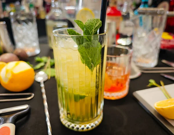 Karışım - profesyonel kokteyl sahnesi otlar, narenciyeler, bar malzemeleri, bardaklar ve içkilerle. Kokteyl hazırlama için mikoloji çalışma alanı