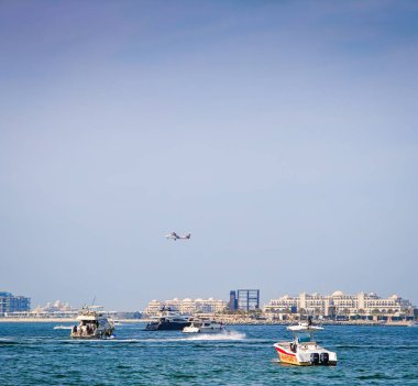 008 2026 - Dubai, BAE. Hava dalışı yapan Dubai uçağı paraşütçülerle birlikte havaalanından havalanıyor. Dubai 'deki JBR plajından panoramik Basra Körfezi manzarası