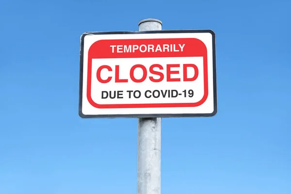 Signo cerrado debido al Coronavirus Covid-19 contra el cielo azul vacío —  Fotos de Stock
