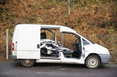 Kırsal kesimde beyaz minibüs tahrip edilmiş ve terk edilmiş.