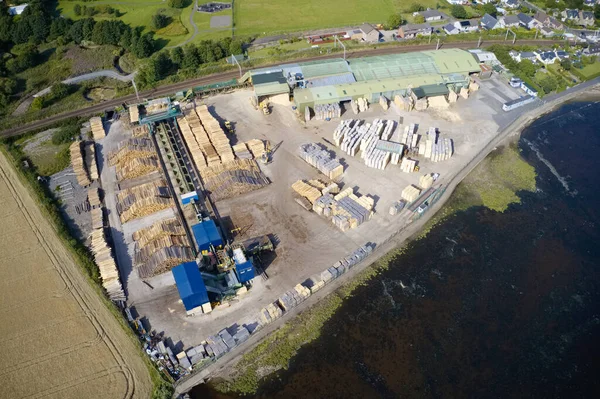 Sawmill aerial view chopped tree wood logs stacks in a row with machinery — Stock Image Sawmill aerial view chopped tree wood logs stacks in a row with machinery Royalty Free Stock Images