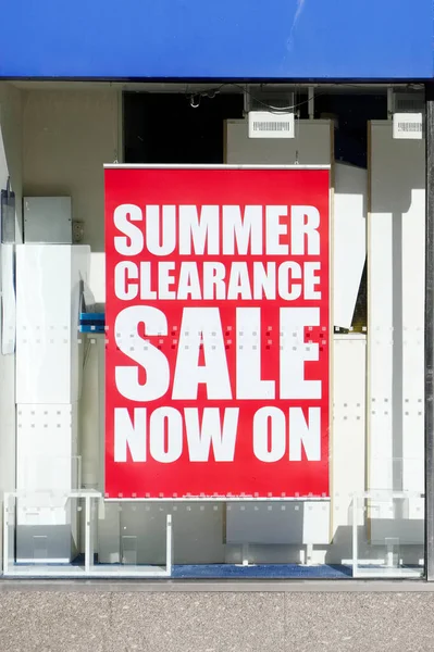 Summer clearance sale now on sign in shop window