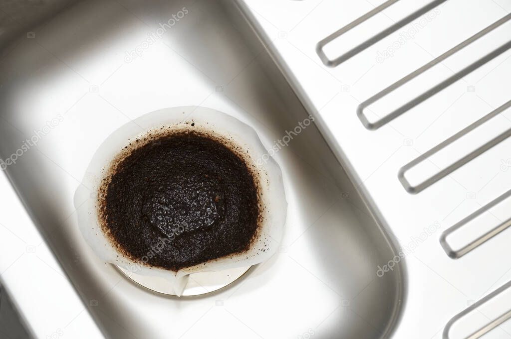 Coffee filter paper draining in kitchen sink plughole