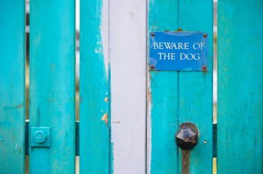 Beware of dog sign on blue wooden house gate clipart