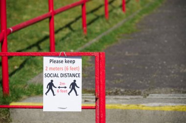 Okul bahçesindeki yol ayrımında sosyal uzaklık tabelası