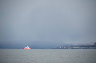 Yalnız kırmızı gemi feribotu Gourock 'a doğru yol alan gri fırtınanın altında.
