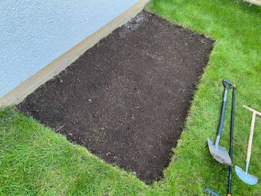 Ev bahçesi çimenliği. Taş zeminin döşenmesine izin vermek için zemin hazırlığı yapılıyor.