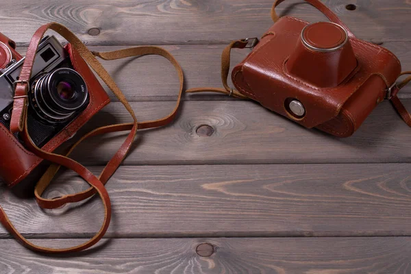 two vintage cameras stand against a background of brown wooden planks with space for copying. top view