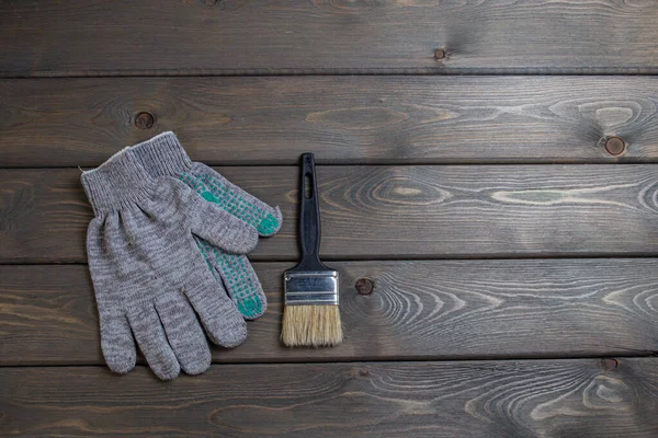 a paintbrush and rag work gloves on a wooden table. top view