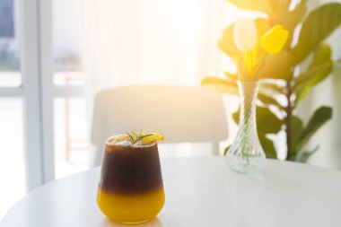 Beyaz arka planda, biberiye ve dilimlenmiş portakalla süslenmiş portakal suyuyla karıştırılmış ferahlatıcı bir bardak buzlu amerikano kahvesi. Sağlıklı yaşam tarzı için alternatif içki. Peyzaj boyutu.