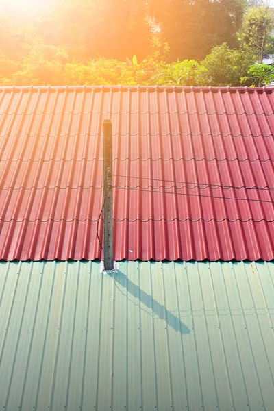 Kırmızı ve yeşil metal çatılı beton bir sütun, çelik çatının dokusu. Portre boyutu.