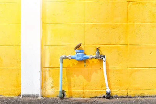 Water meter outside the house, yellow wall background. Measuring device, Open cover of water meter to check counter number of water consumption, water pipe and meter with waterspout of home.