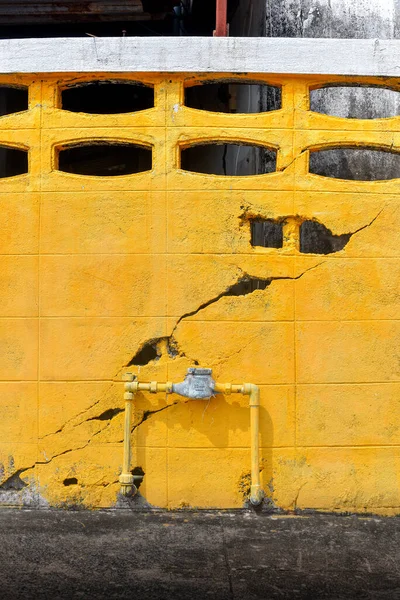 Water meter outside the house, Cracked yellow wall background. Measuring device, Open cover of water meter to check counter number of water consumption, water pipe and meter with waterspout of home. Portrait size.