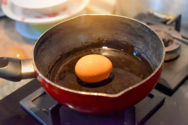 Gaz ocağında güneş ışığıyla kaynayan bir yumurta. Görüntü gürültülü, odaklanma yumuşak..
