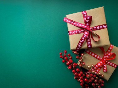 Noel hediyeleri ve kırmızı böğürtlen dalları yeşil arka planda seriliydi. Kopyalama alanı olan düz.