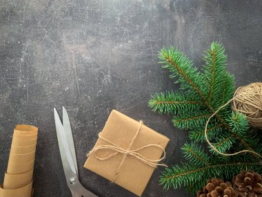 Tahta masadaki antika hediye kutusu. Hediye paketi. Kağıt rulo, ip topu, kozalaklı ladin ve makas. Noel arkaplanını kopyalayan üst görünüm.