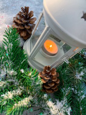 Karda yılbaşı feneri ve güneş ışığıyla aydınlatılmış çam dalı. Mutlu yıllar kartı. Tatil kavramı.