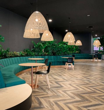 Ahşap zemin ve avizesi, modern mobilyası ve siyah duvarın üstünde bitkileri olan bir kamusal binanın modern iç tasarımı..