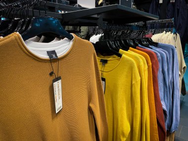 Giyim mağazasının içinde renkli kazaklı askılar..