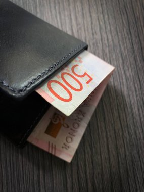 500 İsveç krona banknotu siyah deri cüzdan. Koyu ahşap arka planda izole edilmiş paralı cüzdanın fotoğrafını çek..